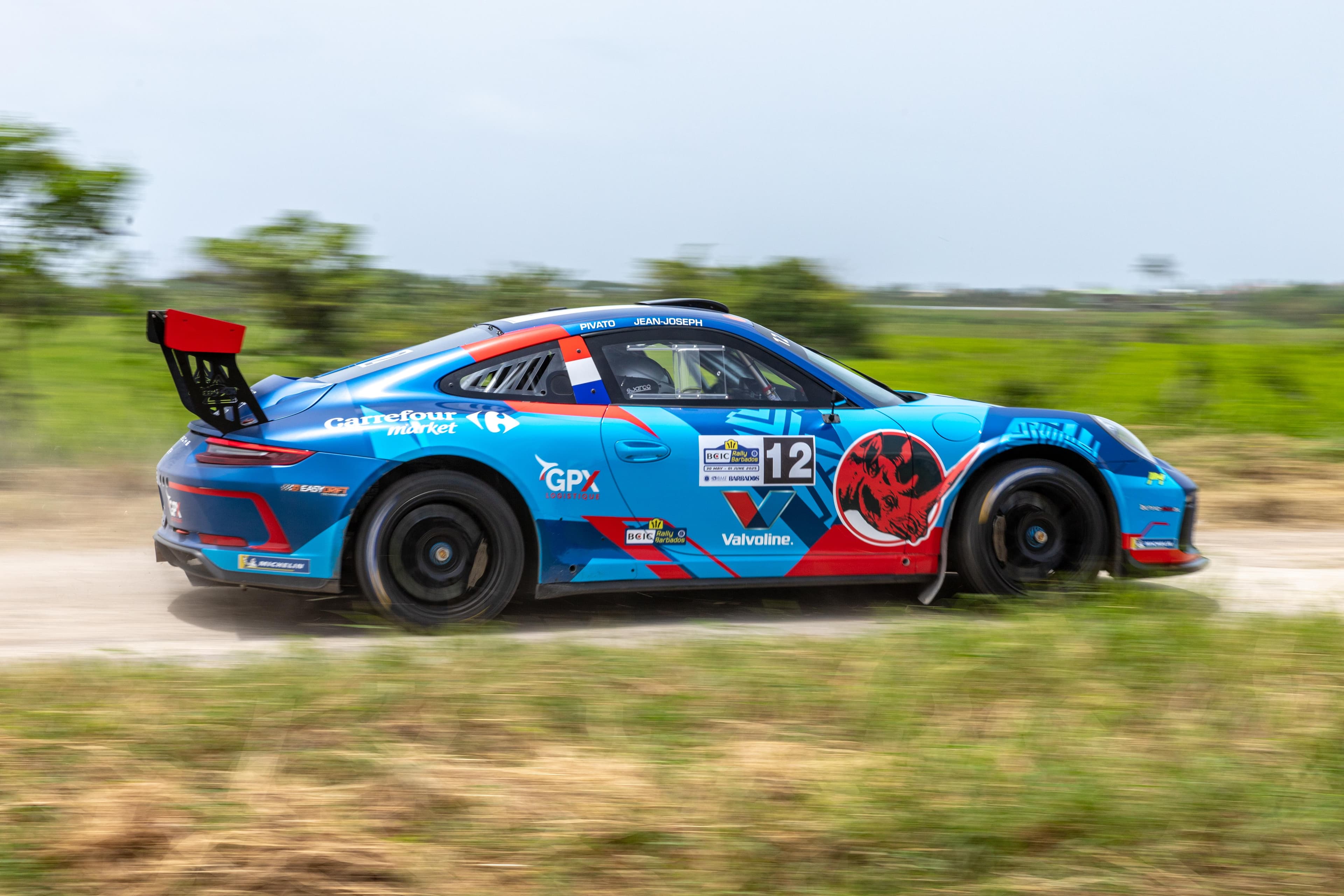 Rally car kicking up dust on a coastal road in Barbados